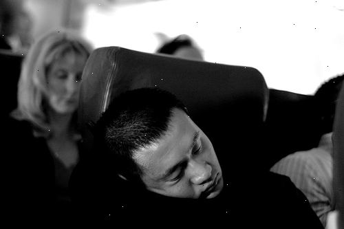 Hvordan sove på flyet. Bestill et vindu sete slik at du kan lene seg mot vinduet og trekk skyggen ned.